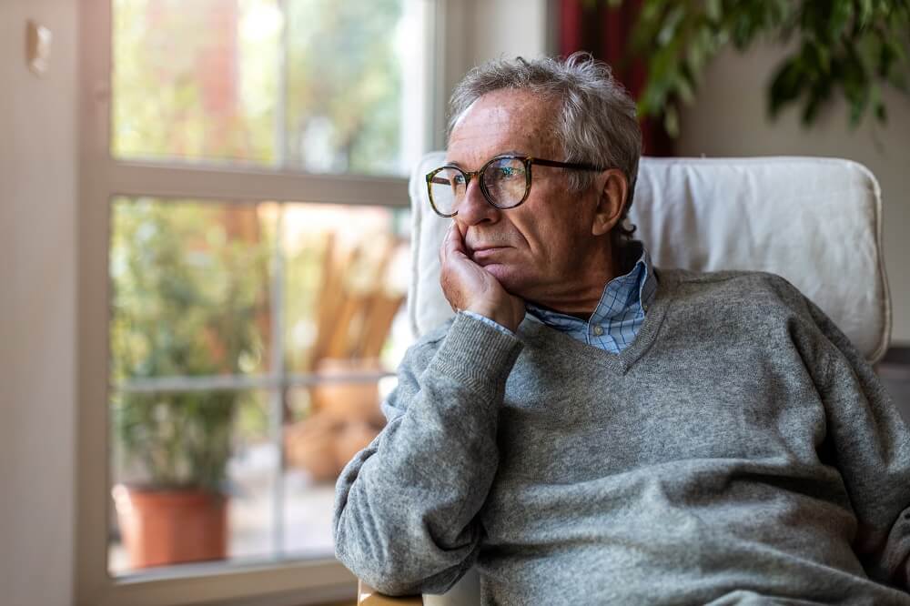 Senior schaut nachdenklich aus dem Fenster