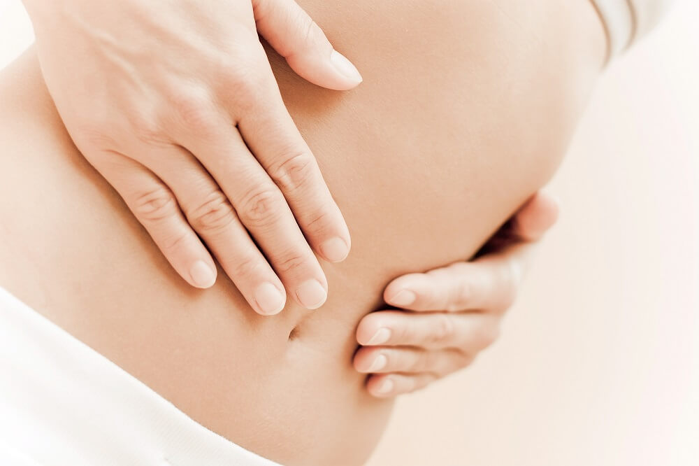 Frau fasst sich an den Bauch