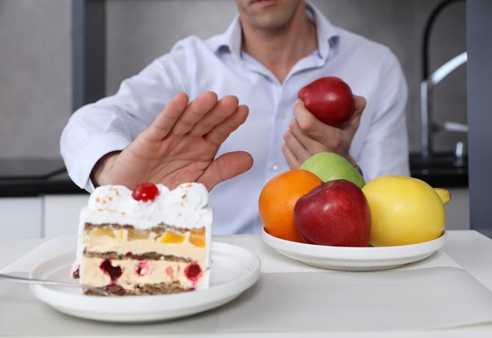 Mann entscheidet zwischen Kuchen und Obst, lehnt den Kuchen ab
