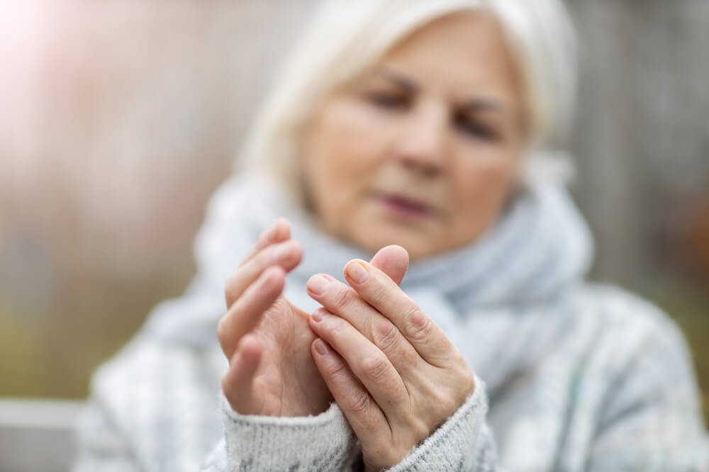 Ältere Dame greift sich an den schmerzenden Daumen mit Arthritis